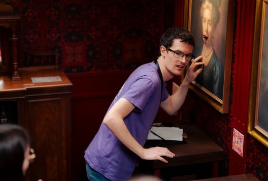 A participant examines a painting in an escape room, checking it carefully for clues.