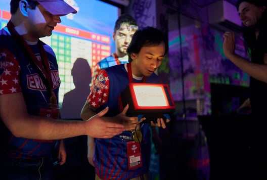 A player is holding the ER Champ trophy while others smile and celebrate nearby.