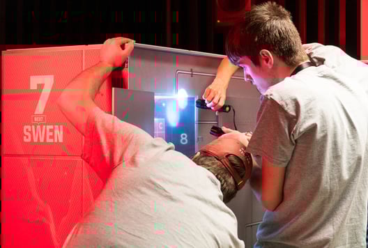 Players solving puzzles inside The Cube during the finals