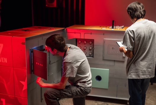Players solving puzzles inside The Cube during the finals